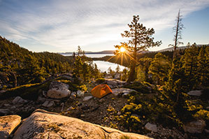 Camping Werbeartikel bedrucken Sie bei laprinta Zelten mitten im Wald zwischen Bäumen im Sonnenuntergang