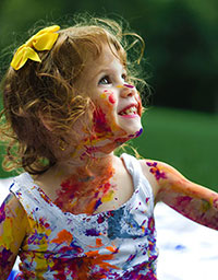 Werbeartikel für Kinder bedrucken Sie bei laprinta Kleines Mädchen mit Schleife im Haar verschmiert mit Farbe