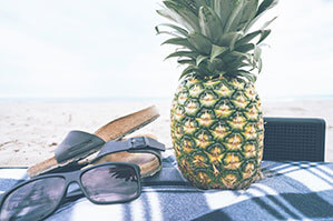 Werbe-Stranddecken bedrucken Sie bei laprinta Stranddecke auf der eine Sonnenbrille, eine Ananas, Lautsprecher und Sandalen liegen