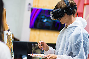 Junger Mann malt mit Virtual-Reality Brille ein Bild