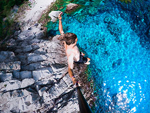 Werbe-Action-Cam bedrucken Sie bei laprinta Klippenspringer, Mann springt von hohem Fels in türkis/blaues Wasser mit einer Action-Cam in der rechten Hand