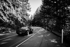 Auto Werbeartikel bedrucken Sie bei laprinta Auto auf einer Straße im Wald neben Bergen