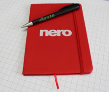 laprinta-Kunde nero ließ bei laprinta ein rotes Notizbuch bedrucken Ein rotes Notizbuch mit Verschlussband und Lesezeichen, auf dessen Deckel n Weiß das nero-Logo gedruckt wurde. Über dem Logo liegt ein Schwarzer Kugelschreiber "Boogie" mit laprinta-Logo.