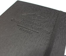 laprinta-Kunde Kempinsky ließ das Notizbuch "Woodlook" prägen Ein schwarzes Notizbuch, das mit einer Holz-Maserung geprägt ist, in welches das Logo des Hotel Kempinsky geprägt wurde