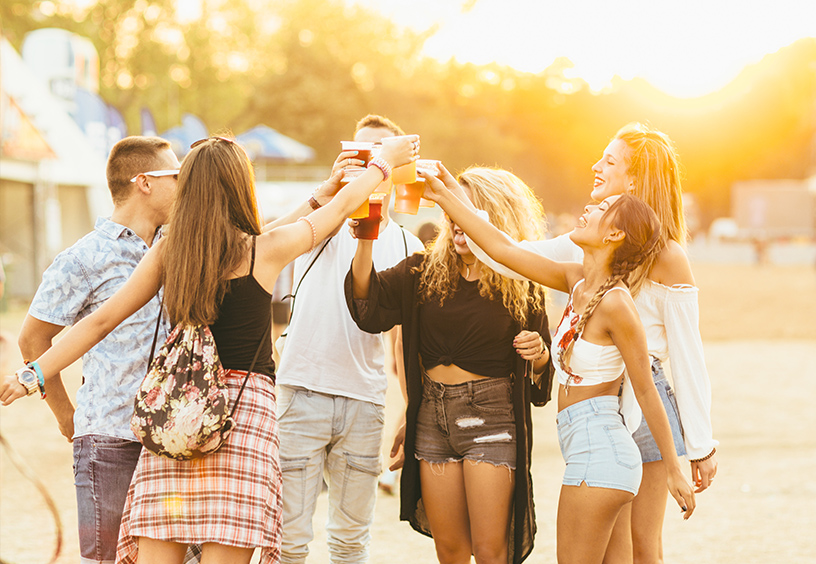 Festival Werbeartikel bedrucken bei laprinta Eine Gruppe junger Leute steht im kreis und streckt die Getränke in die Luft